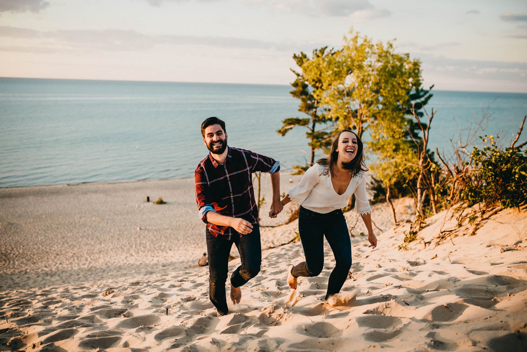 Engagement photo of couple racing up sand dune